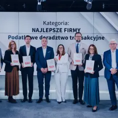 Grupa osób odbiera nagrody na tle ekranu z napisem "Kategoria: Najlepsze Firmy".