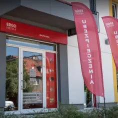 Eleganckie wejście do biura ubezpieczeniowego Ergo Hestia z czerwonym szyldem i dwoma pionowymi banerami.