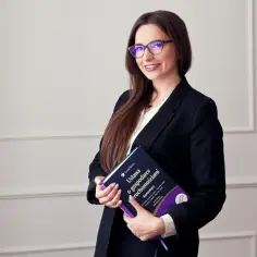Kobieta w okularach i czarnej marynarce trzyma książkę "Ustawa o gospodarce nieruchomościami".
