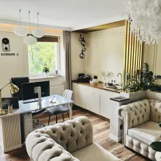 Nowoczesne biuro rachunkowe z wygodną sofą, biurkiem i aneksem kuchennym.