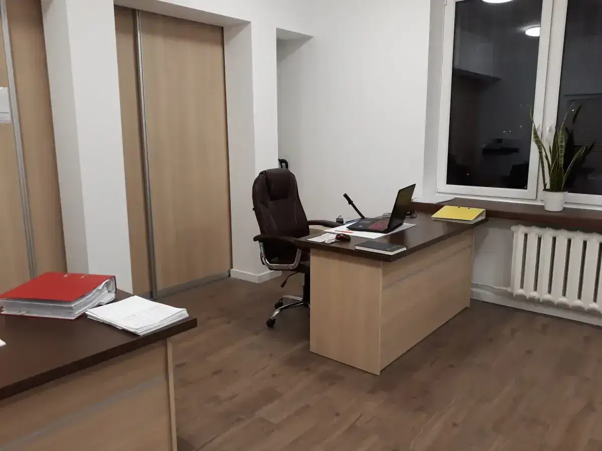 Nowoczesne biuro z biurkiem, laptopem, krzesłem obrotowym i szafą.