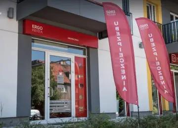 Eleganckie wejście do biura ubezpieczeniowego Ergo Hestia z czerwonym szyldem i dwoma pionowymi banerami.