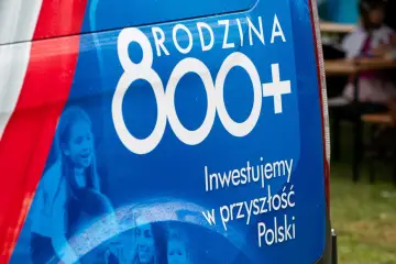 Niebieski baner z napisem "RODZINA 800+" i hasłem "Inwestujemy w przyszłość Polski". W tle widać uśmiechnięte dzieci.